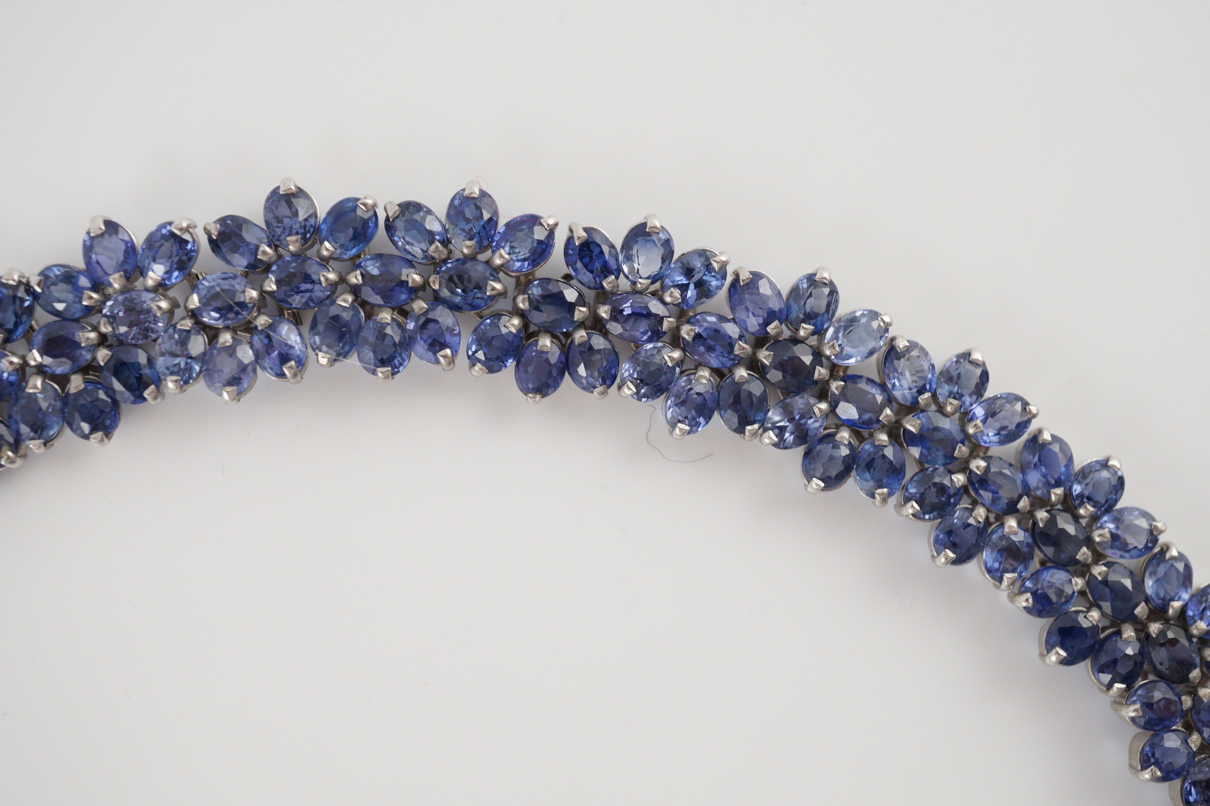 An 18K white gold and synthetic sapphire? flower head cluster set necklace